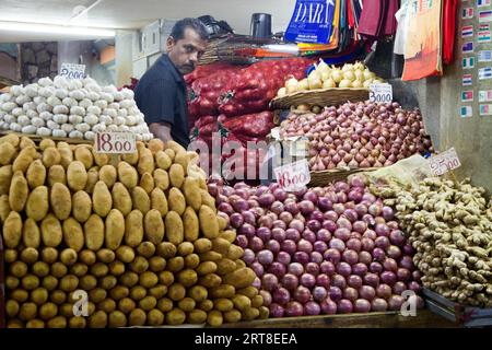 Venditore dietro la sua bancarella al mercato centrale di Port Louis, Mauritius Foto Stock
