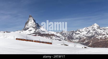 Zermatt, Svizzera, 12 aprile 2017: Un treno rosso di fronte alla montagna innevata del Cervino Foto Stock