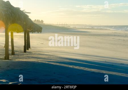 Sovraesposte spiaggia vista serale con molti ombrelloni da sole al tramonto Foto Stock