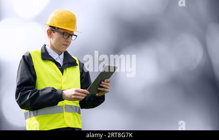 Ritratto di un ingegnere sorridente con occhiali, casco e costume blu che guarda la fotocamera. Isolato... Foto Stock