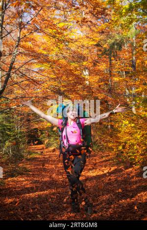 Una felice turista si rallegra in autunno con un'escursione in montagna. Trekking autunnale in montagna. Attività ricreative all'aria aperta. Foto Stock