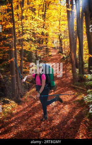 Una felice turista si rallegra in autunno con un'escursione in montagna. Trekking autunnale in montagna. Attività ricreative all'aria aperta. Foto Stock