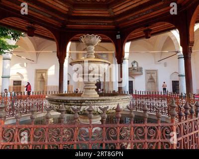 Fontana nel cortile, alias Sahn della Moschea Gazi Husrev-Beg con area di preghiera e Mihrab dietro, Sarajevo, Bosnia ed Erzegovina, 11 settembre 2023 Foto Stock