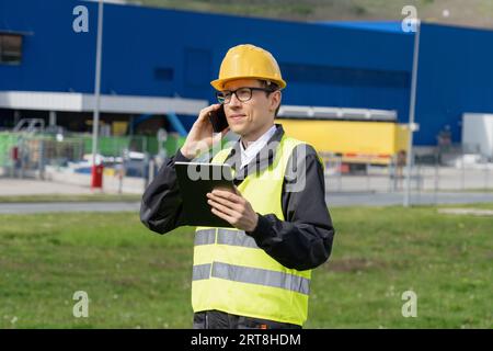 Logistician con telefono e tablet digitale su un background di centro logistico. Foto Stock