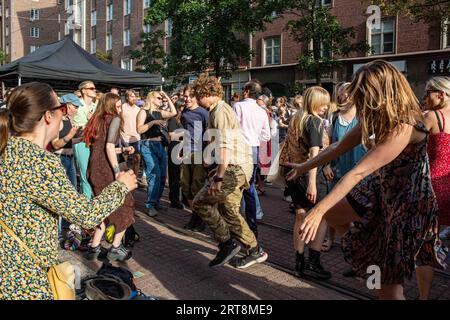 Giovani che ballano per strada al Kallio Block Party 2023 in un soleggiato pomeriggio estivo a Helsinki, Finlandia Foto Stock