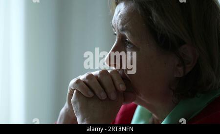 Donna anziana preoccupata immersa nella conversazione ascoltando profondamente la persona fuori dalla fotocamera. Emozione preoccupata degli anziani impegnati con empatia nell'oratore Foto Stock