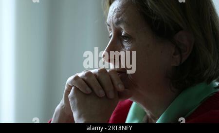 Donna anziana preoccupata immersa nella conversazione ascoltando profondamente la persona fuori dalla fotocamera. Emozione preoccupata degli anziani impegnati con empatia nell'oratore Foto Stock