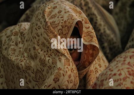 Srinagar, India. 9 ottobre 2023. 10 settembre 2023, Srinagar Kashmir, India: Una sposa musulmana del Kashmir guarda attraverso il velo mentre si siede con altre spose durante un evento di matrimonio di massa a Srinagar. I matrimoni di massa in India sono organizzati da organizzazioni sociali principalmente per aiutare le famiglie economicamente arretrate che non possono permettersi gli alti costi delle cerimonie, così come la dote consueta e i doni costosi che sono ancora prevalenti in molte comunità. Il 10 settembre 2023 a Srinagar Kashmir, India. (Foto di Firdous Nazir/Eyepix Group/Sipa USA) credito: SIPA USA/Alamy Live News Foto Stock