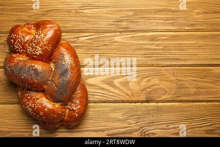 Pane Challah appena sfornato coperto di papavero e semi di sesamo, vista dall'alto su rustico sfondo di legno, tradizionale cucina ebraica festosa. Spazio per Foto Stock