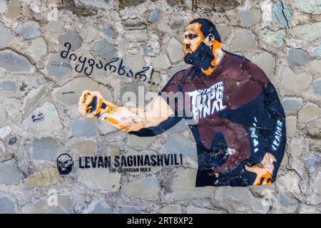 Un graffito a stencil su un muro in pietra naturale a Tbilisi, Georgia, raffigura il lottatore al braccio georgiano Levan Saginashvili con il braccio destro teso. La scritta sotto recita "Levan Saginashvili – The Georgian Hulk". La sua maglietta porta le parole "Top Final", la manica la parola "Leader". A sinistra sono scritte le parole georgiane "მიყვარხარ!..". In inglese: "I love you!..". Nato nel 1988, Saginashvili ha vinto il campionato mondiale di braccio di ferro sette volte. È considerato uno dei più forti lottatori al braccio della storia. Foto Stock