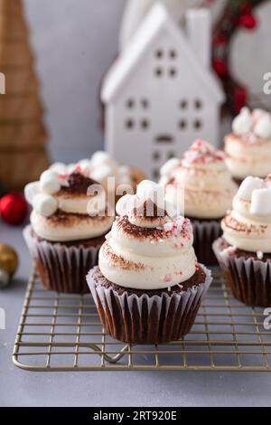 Cupcake di cioccolata calda con mini marshmallow, caramelle alla menta piperita e spolverati con cacao Foto Stock