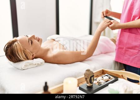 Giovane donna caucasica sdraiata sul tavolo con trattamento di manicure presso il salone di bellezza Foto Stock