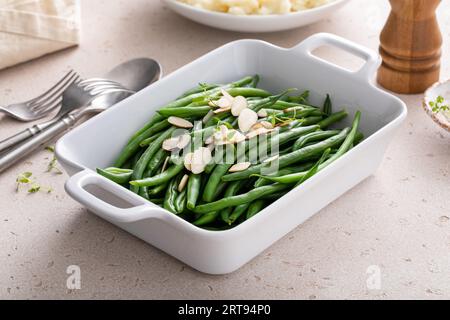 Fagioli verdi conditi con mandorle in un piatto da forno, contorno tradizionale per la cena o la festa di tutti i giorni Foto Stock