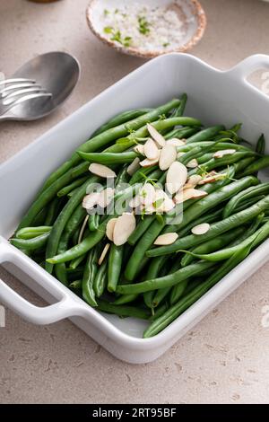 Fagioli verdi conditi con mandorle in un piatto da forno, contorno tradizionale per la cena o la festa di tutti i giorni Foto Stock