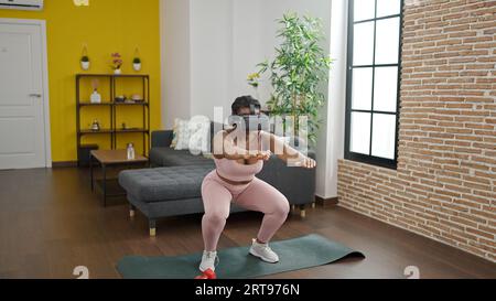 Donne afro-americane allenano le gambe utilizzando occhiali per realtà virtuale a casa Foto Stock