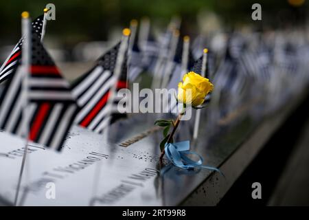 New York, Stati Uniti d'America. 11 settembre 2023. Le bandiere sottili della linea rossa e una rosa gialla in onore dei pompieri che hanno perso la vita decorano i nomi al Ground Zero Memorial durante l'anniversario della commemorazione degli attacchi terroristici del 9/11, l'11 settembre 2023 a New York City, New York. Crediti: TIA Dufour/Homeland Security/Alamy Live News Foto Stock