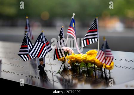 New York, Stati Uniti d'America. 11 settembre 2023. Le bandiere della linea sottile rossa in onore dei vigili del fuoco che hanno perso la vita decorano i nomi al memoriale Ground Zero durante la commemorazione anniversario degli attacchi terroristici del 9/11, l'11 settembre 2023 a New York City, New York. Crediti: TIA Dufour/Homeland Security/Alamy Live News Foto Stock