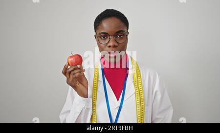 Dietista donna afroamericana che tiene la mela su sfondo bianco isolato Foto Stock