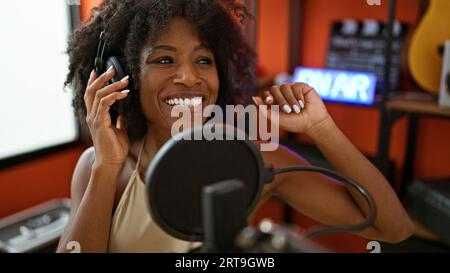 Giornalista radiofonica afro-americana che indossa cuffie che parla allo studio radio Foto Stock