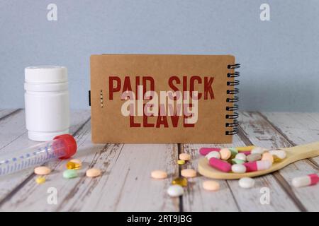 Pillole, test covid e un fonendoscopio medico con l'iscrizione pagato congedo di malattia su sfondo blu. FMLA Family Medical Leave Act Foto Stock