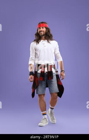 Elegante uomo hippie con camicia bianca su sfondo viola Foto Stock