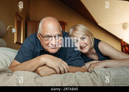 Ritratto di una coppia sposata anziana che si trova sul letto e guarda la fotocamera. Foto Stock