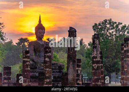 Tramonto presso una statua di Buddha del tempio Wat Mahathat, parco storico di Sukhothai, patrimonio dell'umanità dell'UNESCO, Thailandia, parco storico di Asia Sukhothai, Sukho Foto Stock