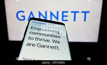 Telefono cellulare con sito Web della società statunitense Gannett Co. Inc. Sullo schermo davanti al logo aziendale. Mettere a fuoco in alto a sinistra sul display del telefono. Foto Stock