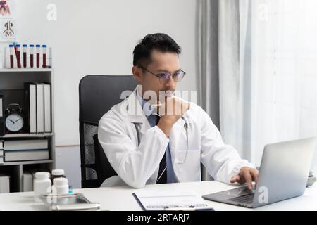 Uomo asiatico sorriso medico pensiero e pazienti usano il computer per spiegare il lavoratore medico o consulenza in conferenza ospedaliera chiamata, telemedicina assistenza sanitaria Foto Stock