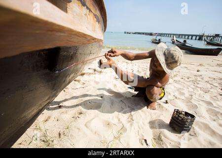 Koh Yao, Thailandia; 1 gennaio 2023: Un pescatore dipinge la sua barca da pesca su un'isola in Thailandia. Foto Stock
