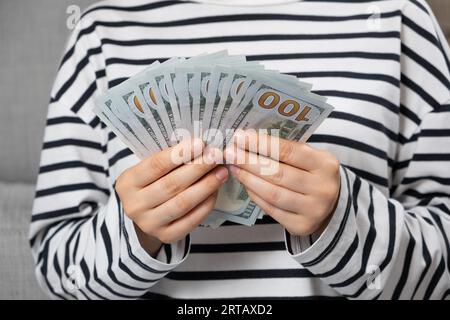 Una donna conta banconote da cento dollari, mani da vicino. Foto Stock