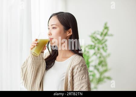 Giovane donna giapponese che beve qualcosa Foto Stock