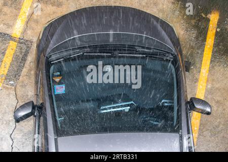 Le gocce di pioggia cadono sull'auto parcheggiata Foto Stock