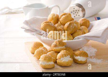 impasto choux o pasta sfoglia alla panna o eclair con ripieni di crema e vaniglia su piatto bianco Foto Stock