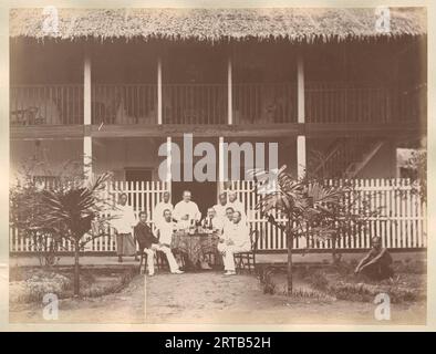 Colonialismo europeo in Indonesia, 1900, 1890, uomini europei, possibilmente proprietari di piantagioni o dirigenti di piantagioni, di fronte al Langkat Hotel con servitori indonesiani. Questa foto è stata probabilmente scattata a Langkat, Sumatra, Foto Stock