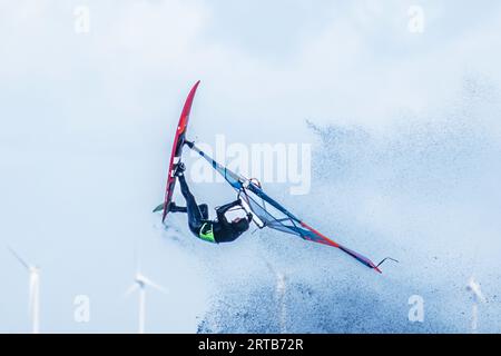 Windsurfer salta di fronte a turbine eoliche, Mar Baltico, Schleswig-Holstein, Germania Foto Stock