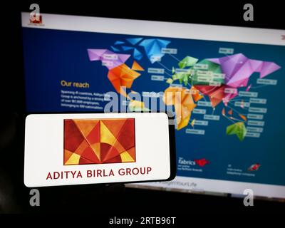 Persona che possiede uno smartphone con il logo della società indiana Aditya Birla Group (ABG) sullo schermo di fronte al sito Web. Concentrarsi sul display del telefono. Foto Stock