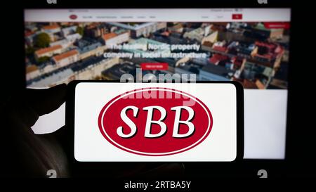 Persona che possiede uno smartphone con il logo di Samhallsbyggnadsbolaget i Norden AB (FFS) sullo schermo di fronte al sito web. Concentrarsi sul display del telefono. Foto Stock