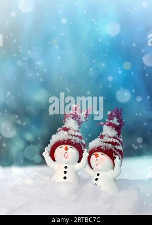 Due pupazzi di neve sulla neve in inverno. Sfondo natalizio con un simpatico pupazzo di neve. Biglietto di Natale, spazio per le copie. Foto Stock