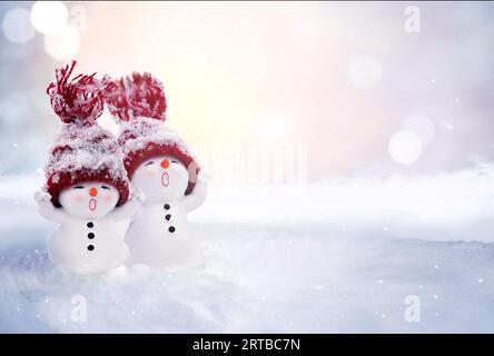 Due pupazzi di neve sulla neve in inverno. Sfondo natalizio con un simpatico pupazzo di neve. Biglietto di Natale, spazio per le copie. Foto Stock