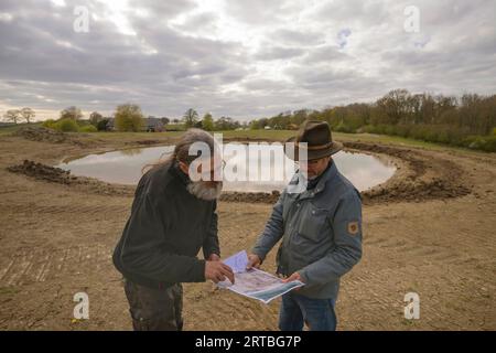 Biotopo per anfibi è stato creato di recente, gli uomini controllano i lavori di costruzione, Germania, Schleswig-Holstein Foto Stock