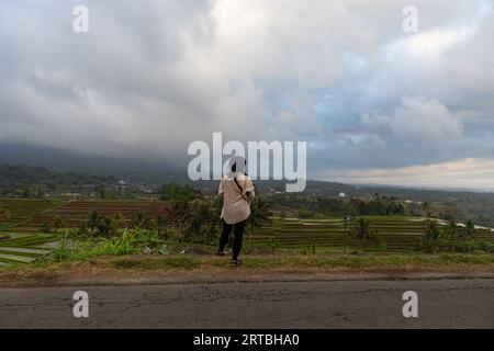 Una ragazza indonesiana che ammira i paesaggi mozzafiato delle risaie terrazzate dell'UNESCO a Jatiluwih, Bali, Indonesia. Foto Stock