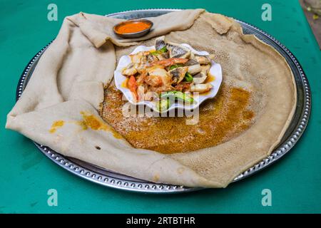 Pasto in Etiopia - peperoncino con peperoncino e verdure su pane piatto injera Foto Stock