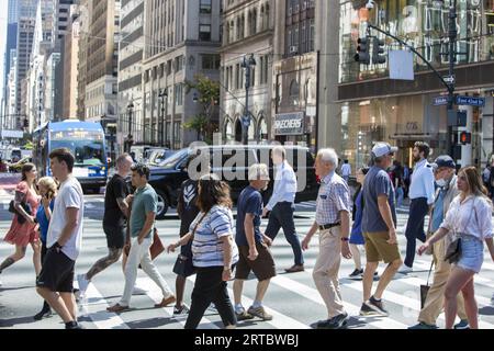 Persone e traffico stradale all'angolo sempre affollato tra la 42nd Street e la 5th Avenue nel centro di Manhattan. Foto Stock