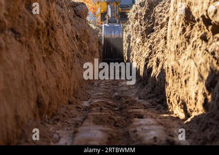 Escavatore che scava un fossato per la fondazione di una piccola casa Foto Stock