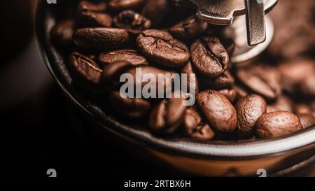 Un'immagine ravvicinata di un macinacaffè che pesa chicchi di caffè appena macinati su un tavolo di legno Foto Stock