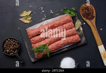 Salsicce crude al kebab di lula su tavola e spezie, vista dall'alto Foto Stock