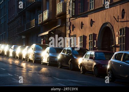 Le auto sono parcheggiate in fila lungo la vecchia strada della città Foto Stock