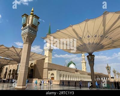 Medina, Arabia Saudita - 22 agosto 2023: I pellegrini camminano sotto ombrelli giganti nel complesso della Moschea Nabawi. Baldacchino a Masjid Nabawi a Medina, in Arabia Saudita Foto Stock