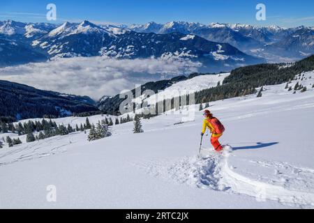 Donna in tour sciistico scendendo da Wiedersberger Horn, Tux Alps e Karwendel sullo sfondo, Wiedersberger Horn, Kitzbühel Alps, Tirolo, Austria Foto Stock
